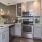 Spacious and well lit kitchen with wood floors and stainless steel appliances. 