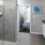 Large well lit bathroom with large mirror and white cabinets with a spacious walk in closet.