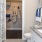 Large well lit bathroom with large mirror and white cabinets with a spacious walk in closet.